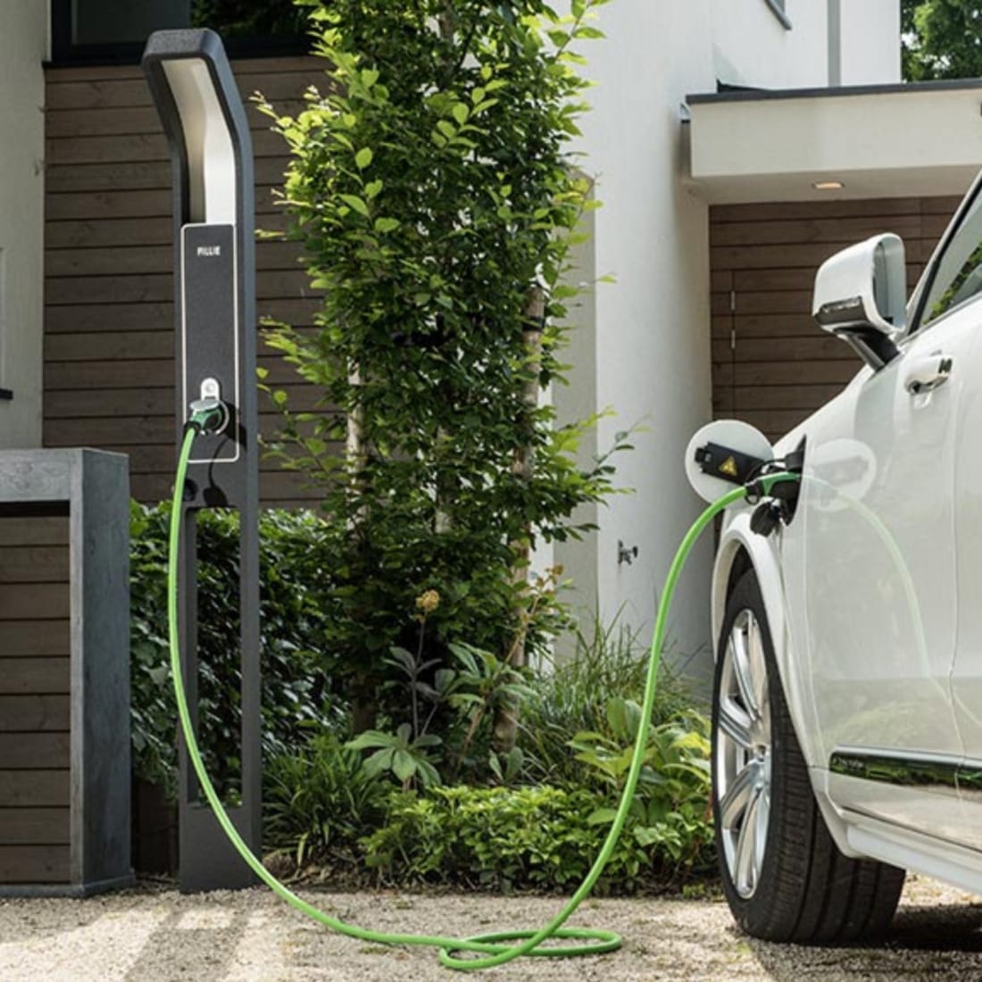 laadpaal voor elektrische auto subtiel geïntegreerd in groene tuin.