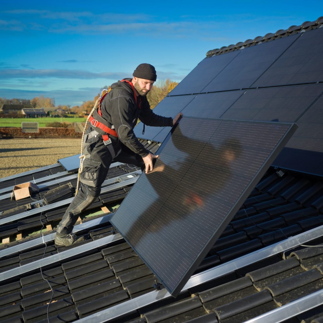 transport en montage van zwarte zonnepanelen op dak door installateur.