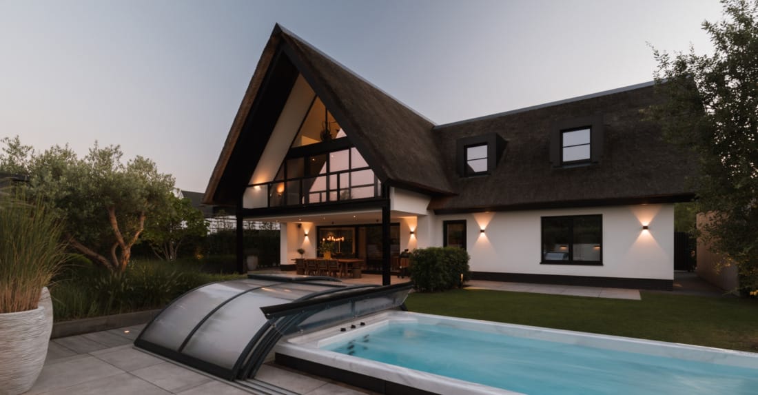 luxe bijgebouw met zwembad en terrasverwarming in de avond.
